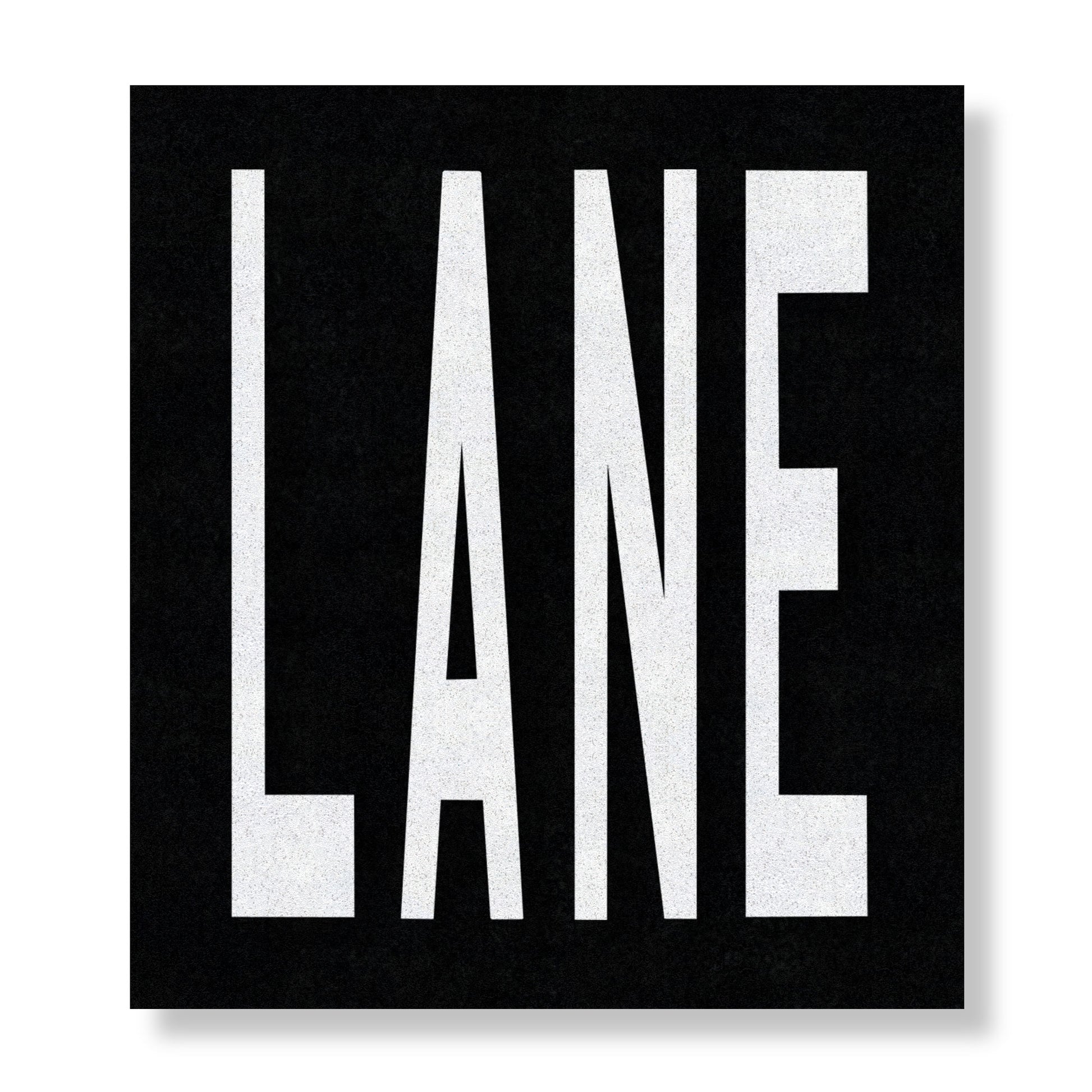 White preformed thermoplastic text LANE in all capital letters on a black rectangle.