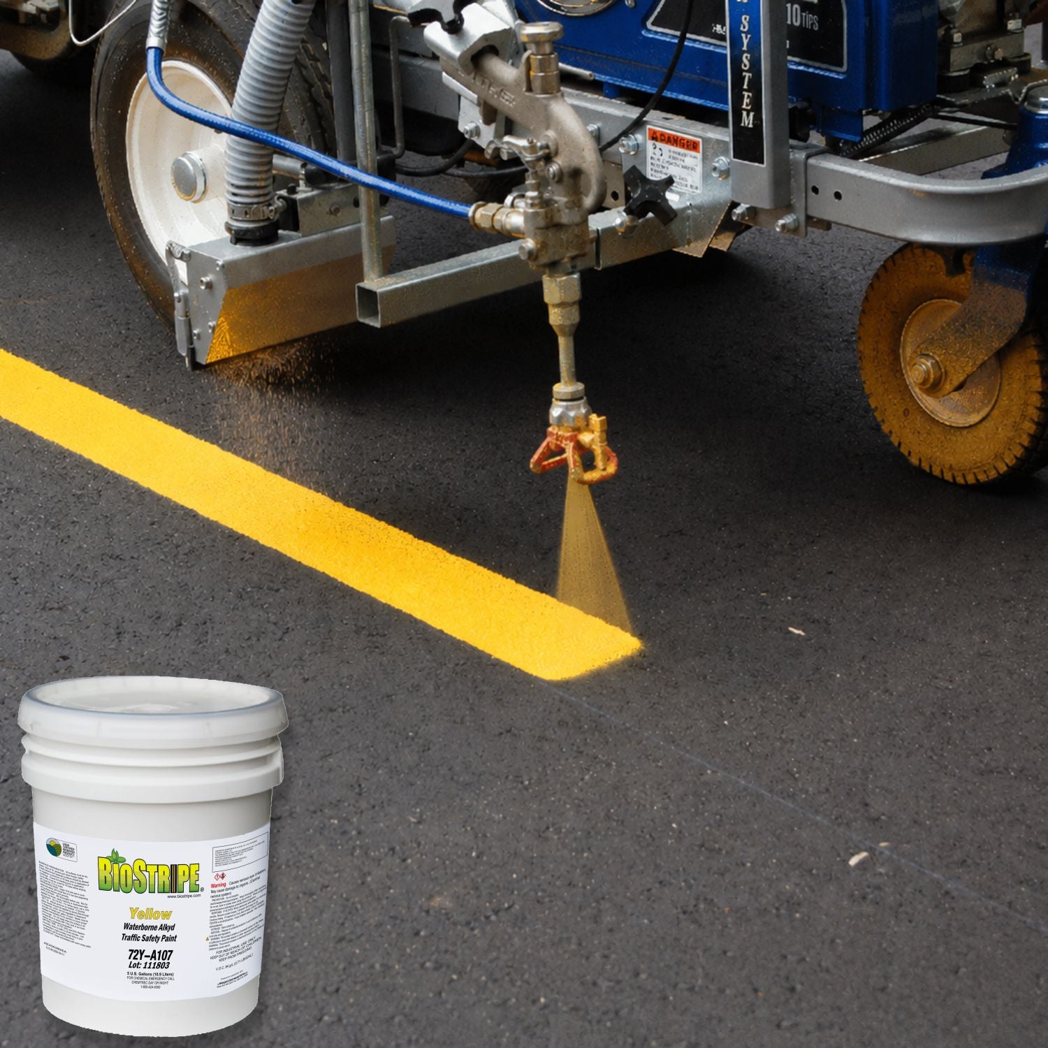 BioStripe Yellow Waterborne Alkyd Traffic Paint being spray-applied to create a bright yellow pavement line on asphalt using a professional striping machine.