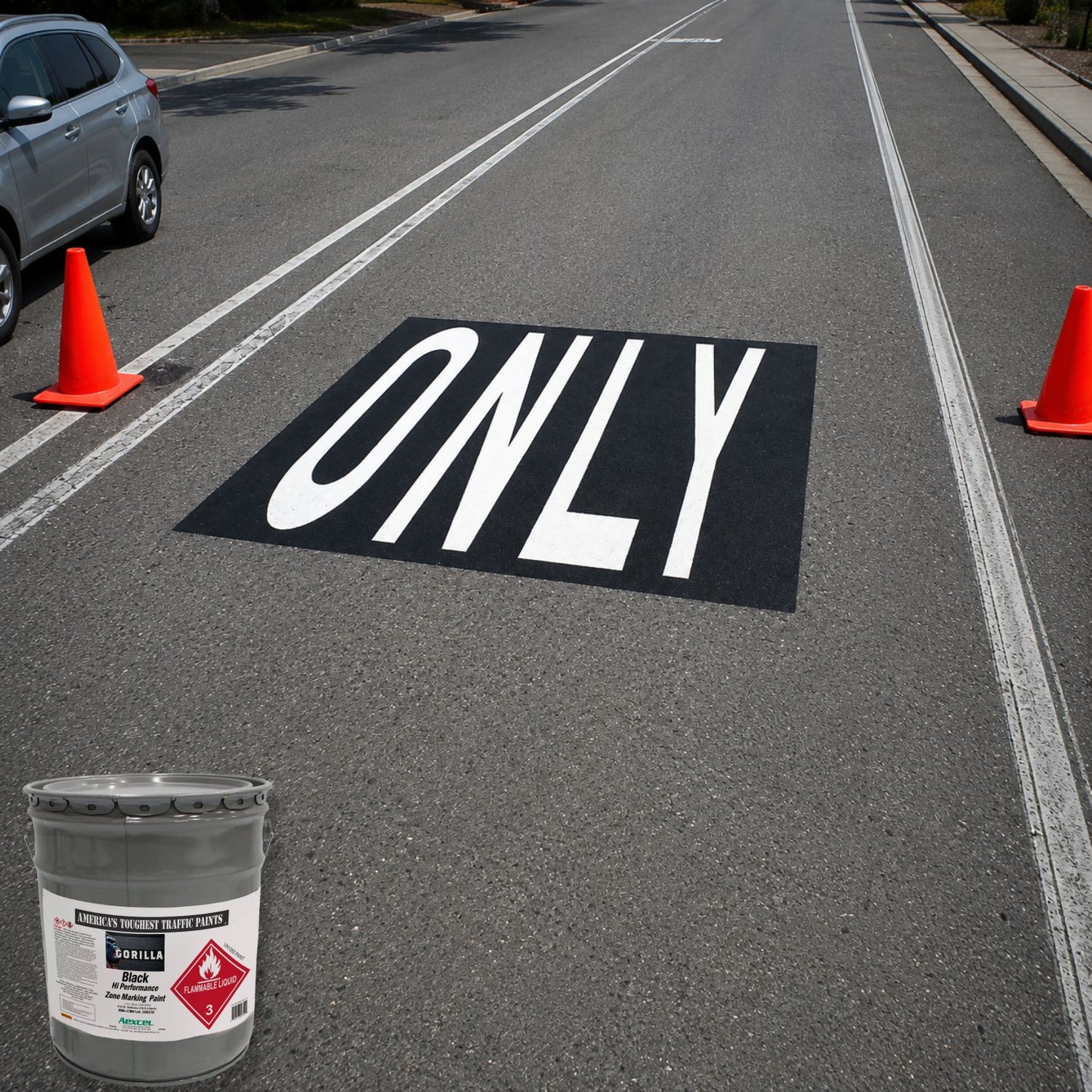Roadway lane marking featuring the word “ONLY” in large white letters on a black rectangular background, centered between lane lines on an asphalt street.