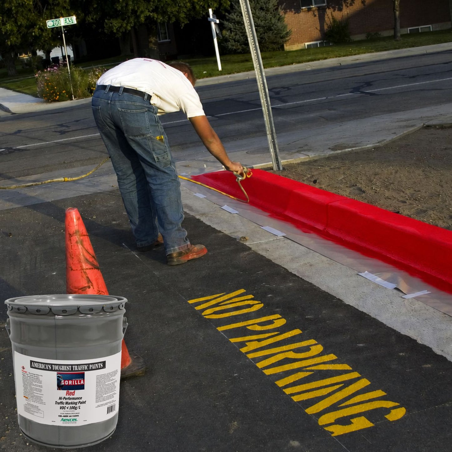 Worker applying red Gorilla traffic marking paint to a fire lane curb with no-parking pavement markings.