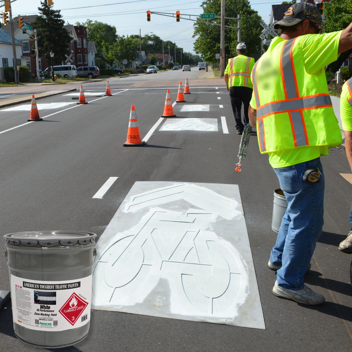 Road crew applying a white bicycle lane stencil on newly paved asphalt using Aexcel Gorilla Traffic Marking Paint for durable, high-visibility bike lane markings.