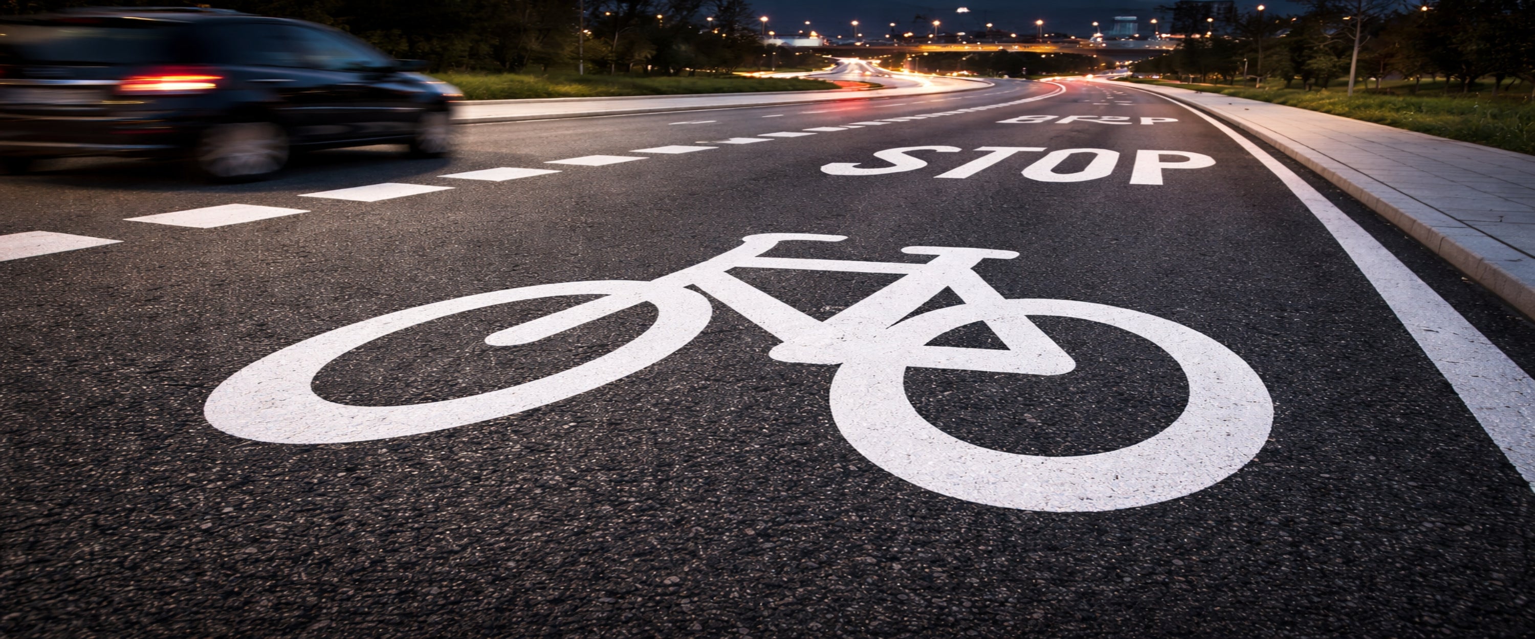 Preformed thermoplastic bike lane symbol and STOP road marking on city street at night.