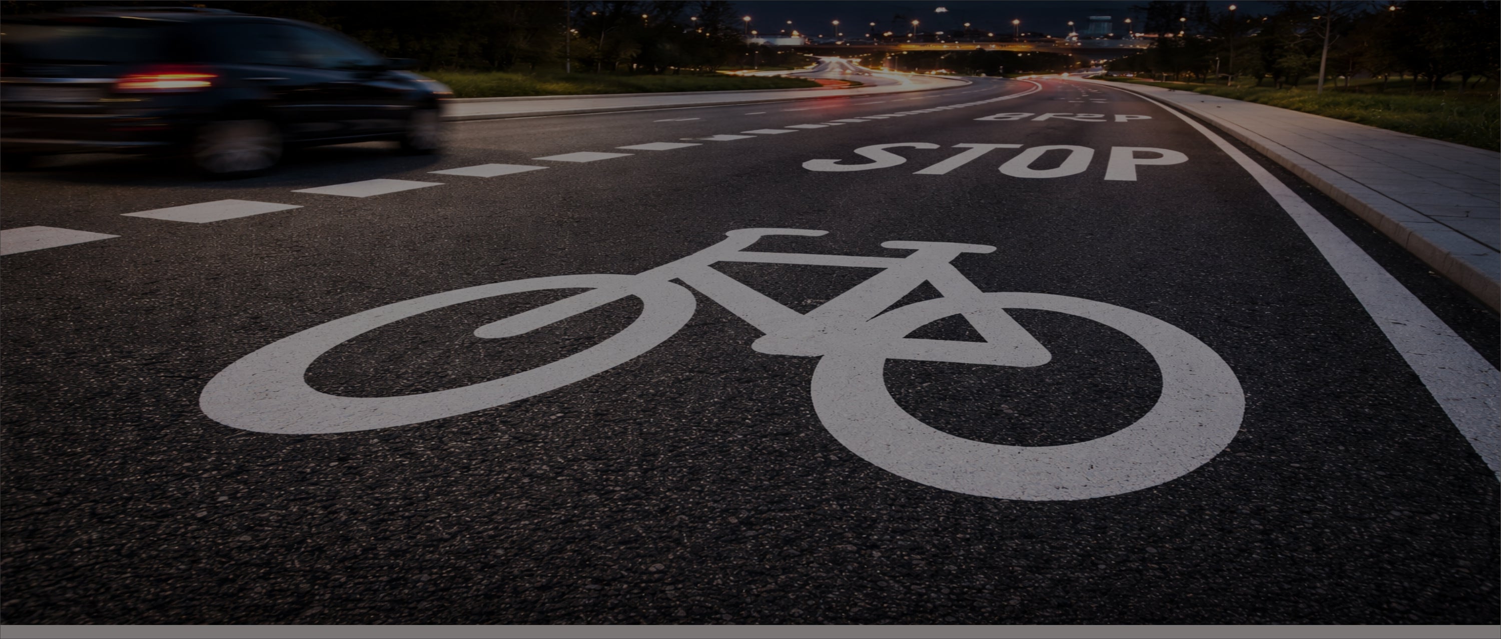Preformed thermoplastic bike lane symbol and STOP road marking on city street at night.