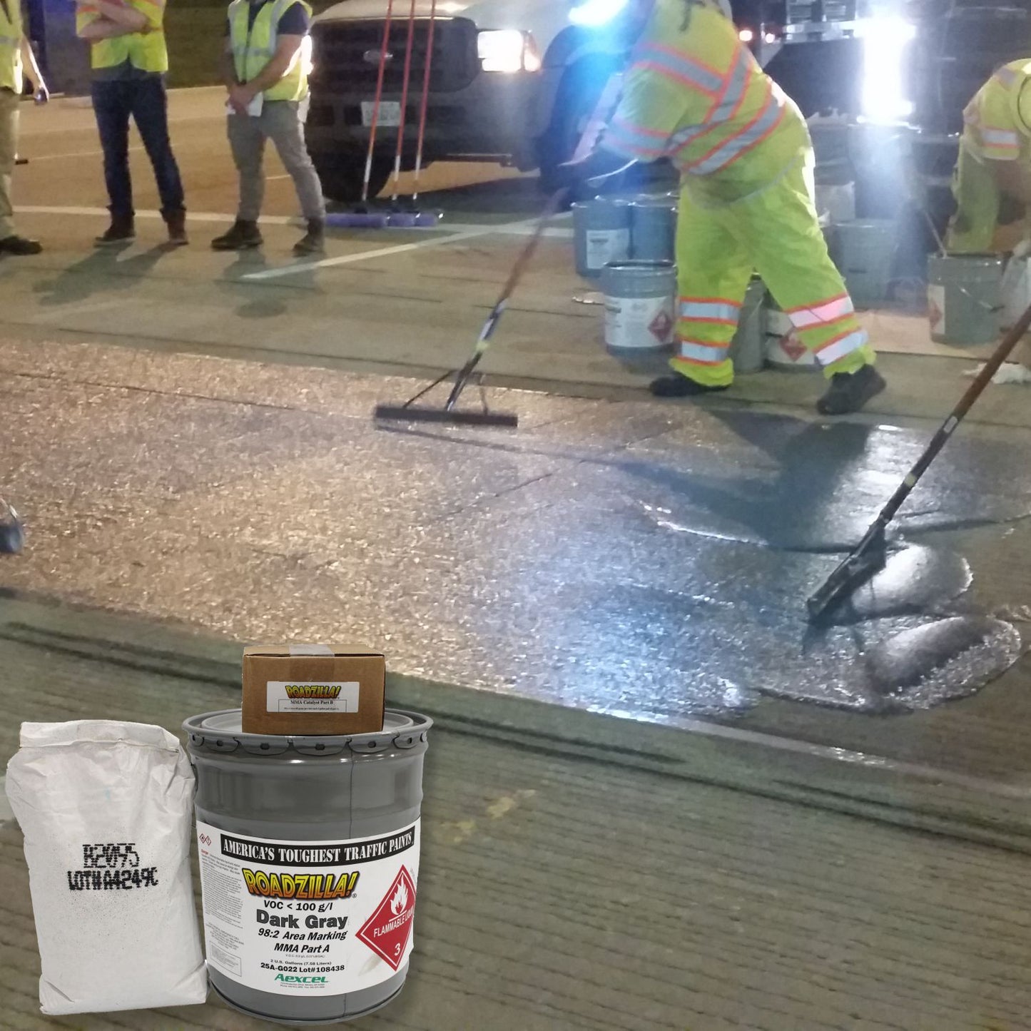 RoadZilla Dark Gray MMA area marking system being applied to a roadway surface for high-friction anti-skid pavement treatment.