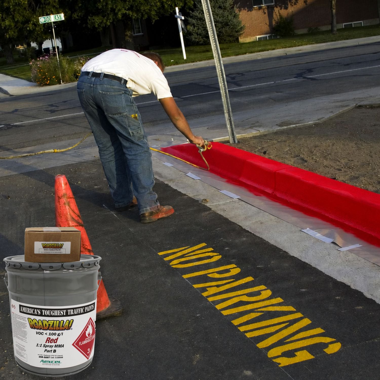 Worker applying RoadZilla Red MMA traffic marking paint to a fire lane curb while "NO PARKING" pavement markings are visible on newly paved asphalt.