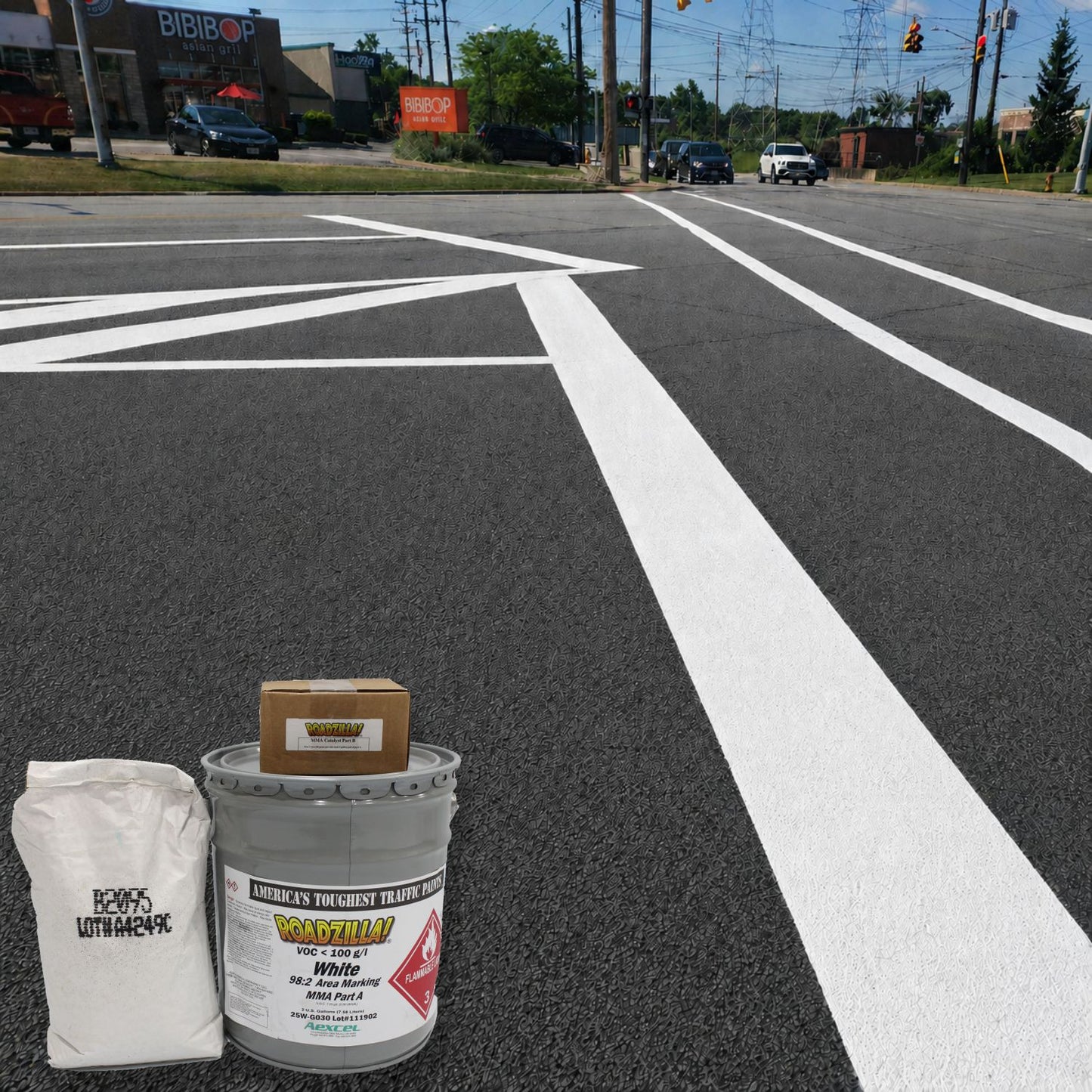RoadZilla White MMA Area Marking System components displayed in front of freshly applied white roadway striping at a signalized intersection.