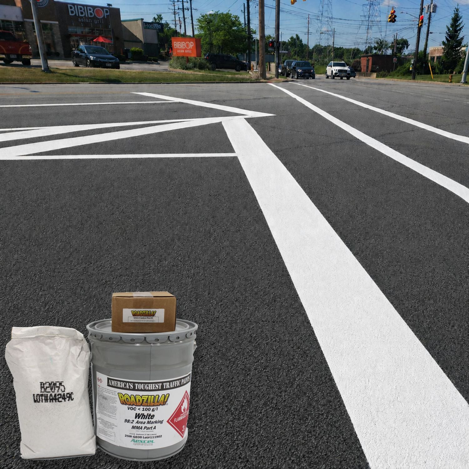 RoadZilla White MMA Area Marking System components displayed in front of freshly applied white roadway striping at a signalized intersection.